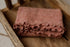 Primrose pink floral textured newborn photography wrap with delicate ruffle trim, folded inside a rustic wooden prop.