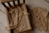 Toffee-colored stretchy mesh newborn wrap with a raised dot texture draped over a small wooden photography bed.
