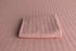 Baby pink newborn photography posing fabric and matching knit wrap with a soft, textured cable-knit pattern.
