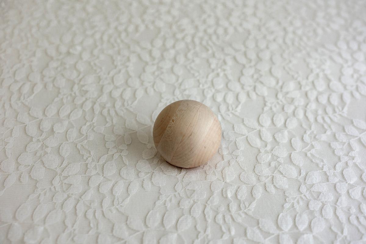Minimalist ivory lace fabric drop for newborn photography featuring a delicate raised leaf pattern and soft neutral texture.