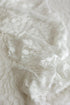 Soft ivory embroidered lace layer draped in loose folds, showing sheer fabric and raised leaf details for newborn photography.