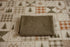 A hunter green newborn photography waffle knit wrap placed on top of a patchwork quilted tablecloth with pine tree and plaid patterns.