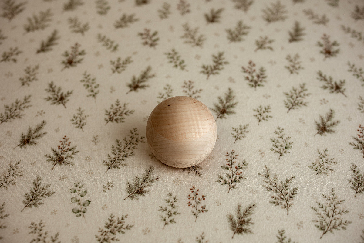 Mantle Garland newborn photography posing fabric featuring delicate evergreen sprigs, greenery, and berries on a warm cream background.