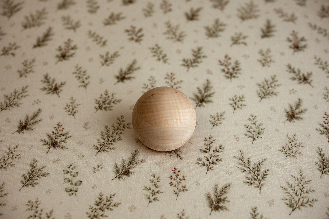 Mantle Garland newborn photography posing fabric featuring delicate evergreen sprigs, greenery, and berries on a warm cream background.