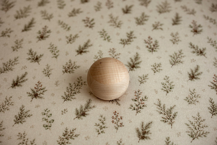 Mantle Garland newborn photography posing fabric featuring delicate evergreen sprigs, greenery, and berries on a warm cream background.