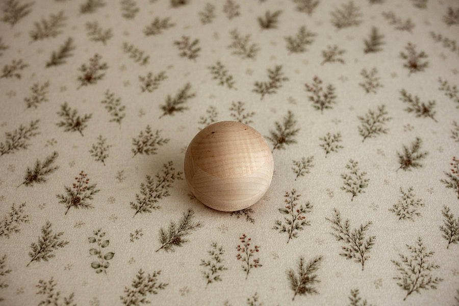 Mantle Garland newborn photography posing fabric featuring delicate evergreen sprigs, greenery, and berries on a warm cream background.