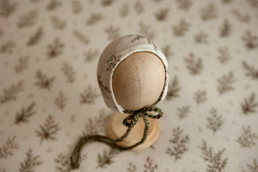 Mantle Garland newborn photography bonnet featuring delicate evergreen branches on cream fabric with coordinating olive green ties.