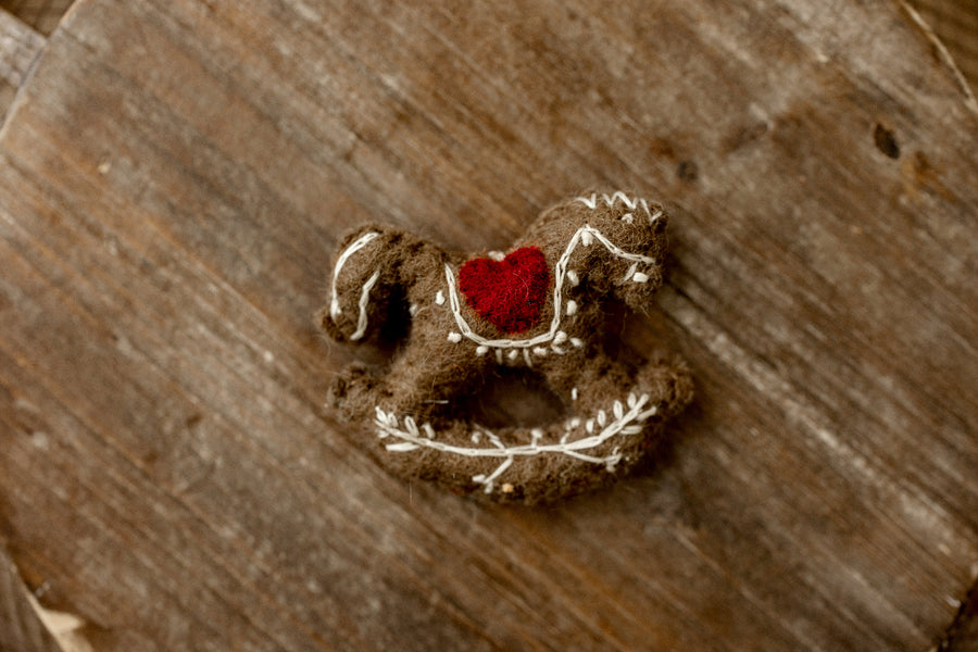 Vintage-inspired brown felted rocking horse newborn photography lovie with cream embroidered details and a red heart accent.