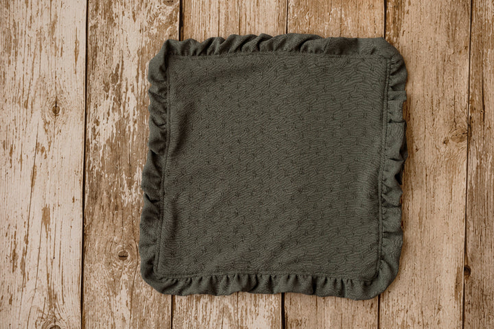 Olive green ruffled mini blankie for newborn photography, styled on a wooden poly paper backdrop.