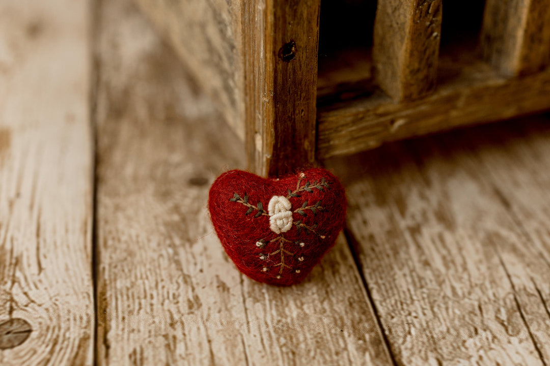 Deep red felted heart newborn photography lovie featuring delicate cream floral embroidery and green botanical details for Christmas portraits.