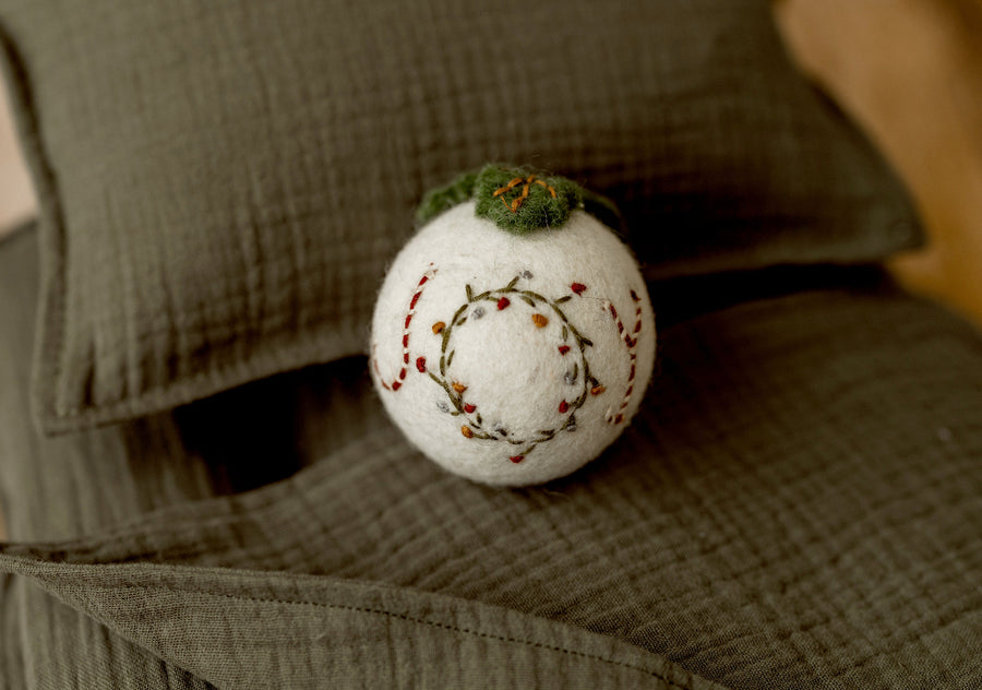 Cream felted Christmas ornament newborn photography lovie with embroidered greenery, festive red accents, and green ornament topper.