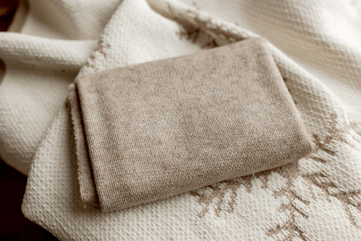 Folded tan jersey fabric layered over a cream-colored textured knit wrap for newborn photography.