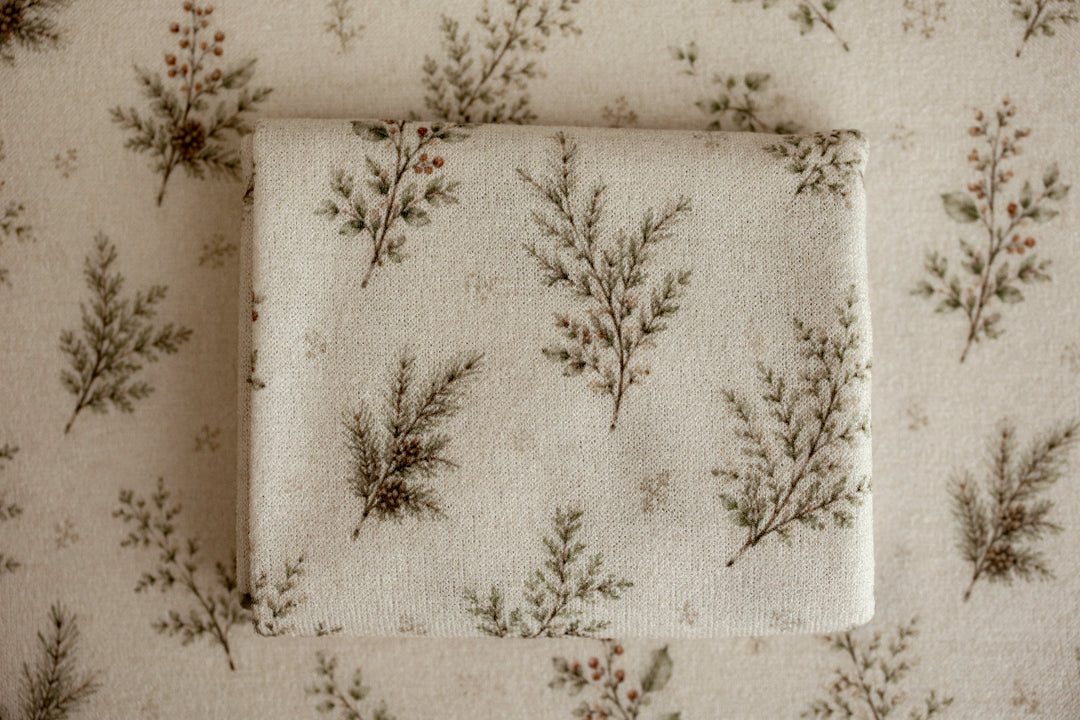 Close-up of Mantle Garland cream newborn posing fabric and coordinating wrap featuring delicate evergreen branches and botanical details used for newborn photography.