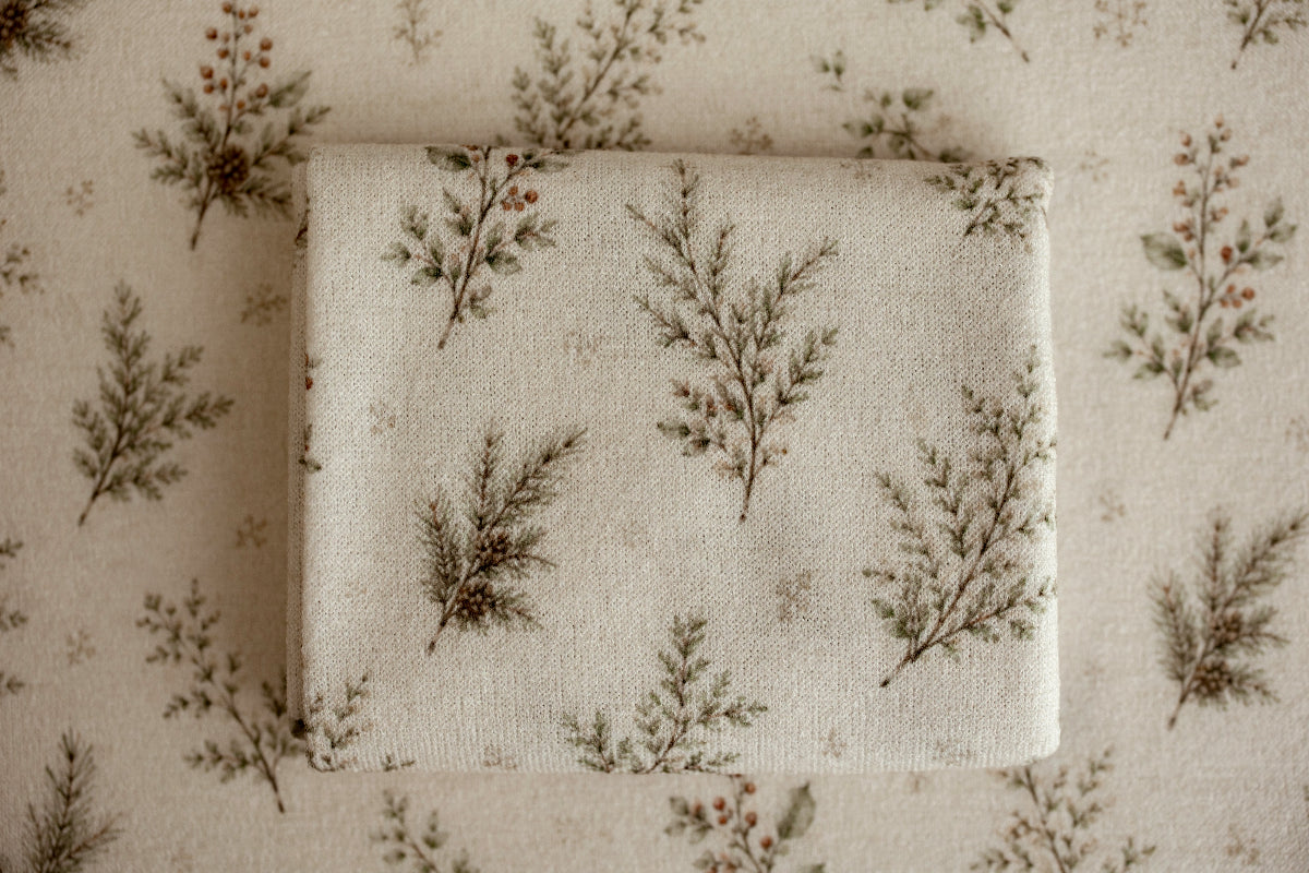 Close-up of Mantle Garland cream newborn posing fabric and coordinating wrap featuring delicate evergreen branches and botanical details used for newborn photography.