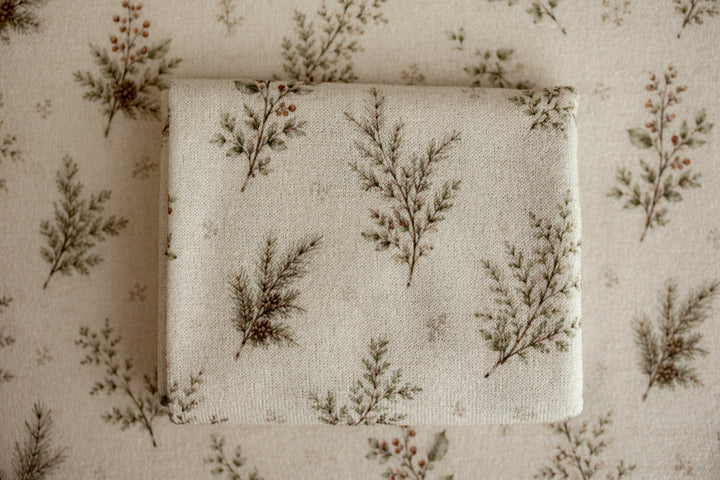Close-up of Mantle Garland cream newborn posing fabric and coordinating wrap featuring delicate evergreen branches and botanical details used for newborn photography.