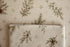 Close-up of Mantle Garland cream newborn posing fabric and coordinating wrap featuring delicate evergreen branches and botanical details.