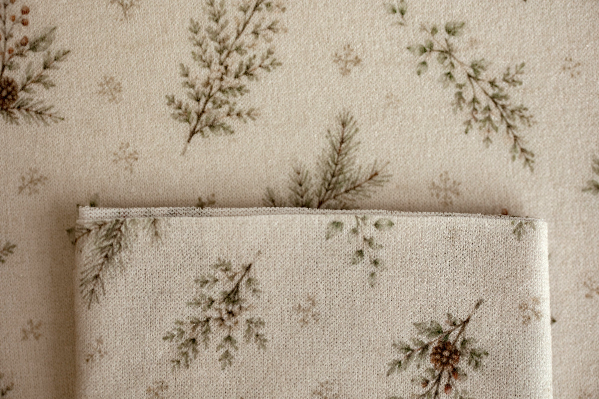 Close-up of Mantle Garland cream newborn posing fabric and coordinating wrap featuring delicate evergreen branches and botanical details.