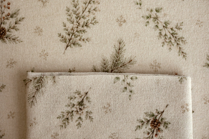 Close-up of Mantle Garland cream newborn posing fabric and coordinating wrap featuring delicate evergreen branches and botanical details.
