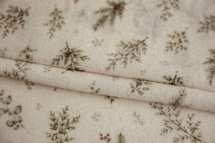 Close-up of Mantle Garland cream newborn posing fabric and coordinating finished edge wrap featuring delicate evergreen branches and botanical details.