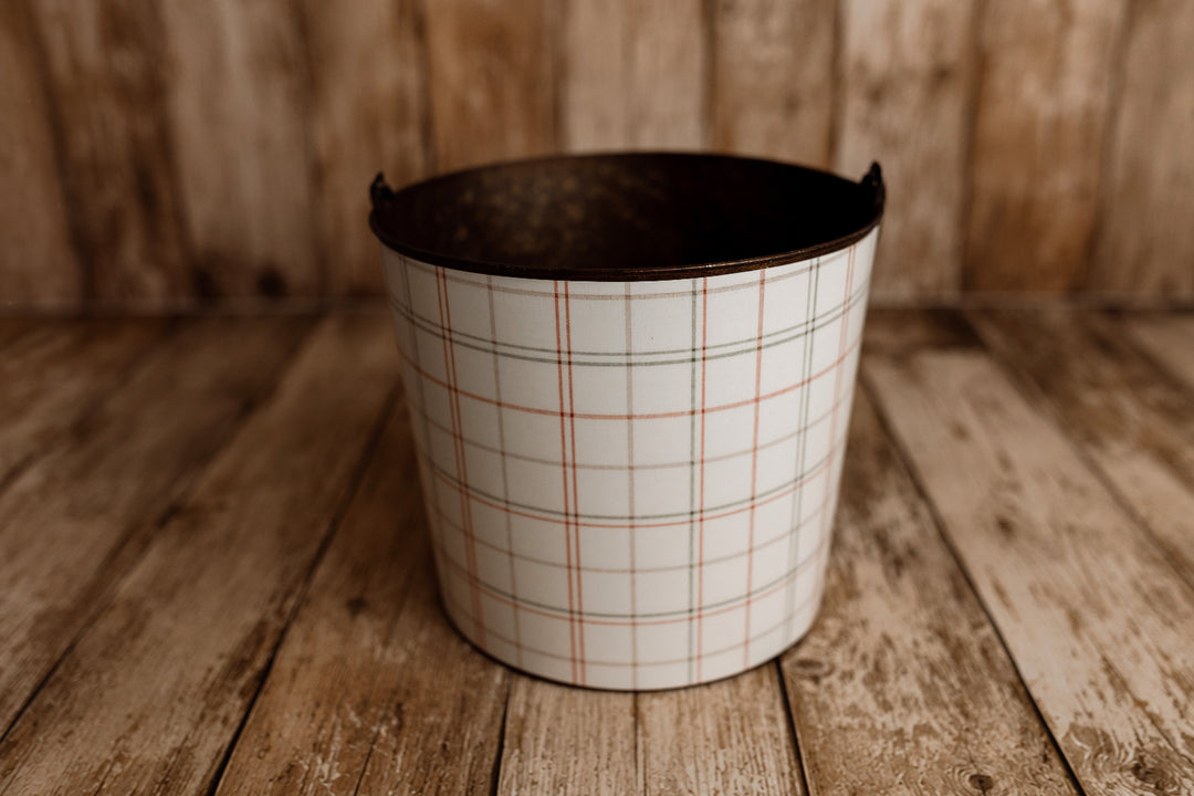 Vintage metal newborn posing bucket styled with Cabin Curtains removable plaid bucket cover in soft farmhouse Christmas colors.