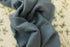 Soft, stretchy dusty blue fabric draped over a cream-colored floral posing backdrop for newborn photography.