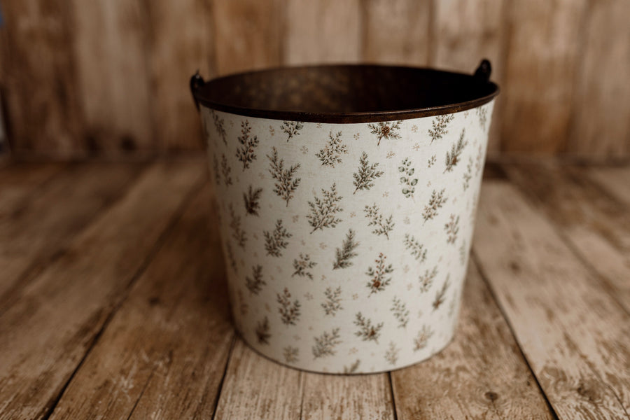Product photo: Rustic metal newborn posing bucket with Mantle Garland botanical Christmas bucket cover featuring evergreen sprigs and subtle berries.