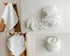 White newborn photography props featuring a delicate metallic gold star pattern on soft white fabric, including a ruffled mini blanket, matching newborn pillow and sheet set, and coordinating white knit wrap for newborn photo sessions.