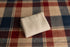 Folded cream-colored waffle knit fabric resting on a red, white, and blue plaid background.