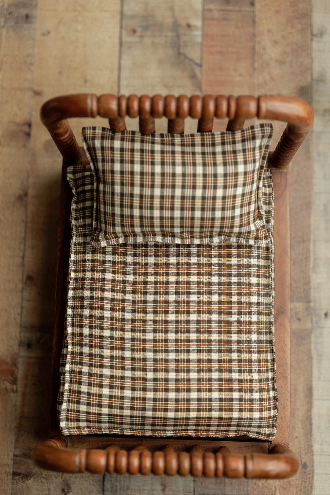 Brown plaid newborn photography sheets styled in a wooden prop bed, designed to coordinate with the Nest | Coffee Bean wrap and pillowcase.