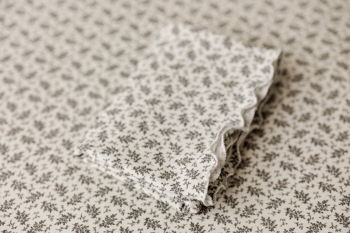Ditzy floral ruffle newborn wrap folded on matching posing fabric backdrop