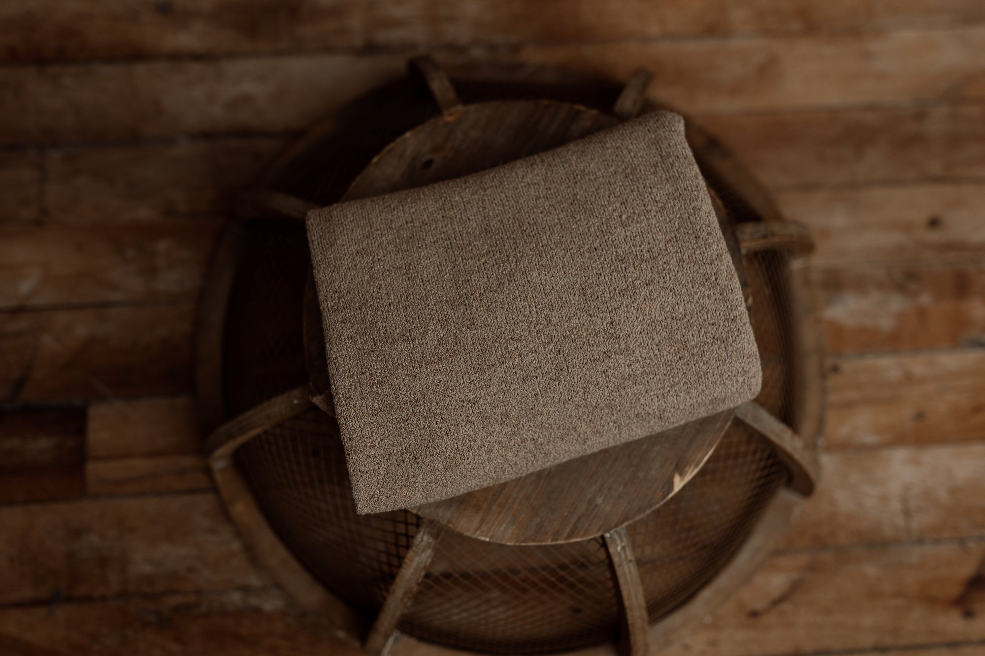 Nest Collection newborn wrap in Coffee Bean, a warm textured brown tone designed to coordinate with brown plaid sheets and pillowcase for photography props.