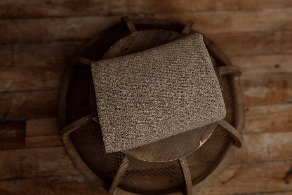Nest Collection newborn wrap in Coffee Bean, a warm textured brown tone designed to coordinate with brown plaid sheets and pillowcase for photography props.