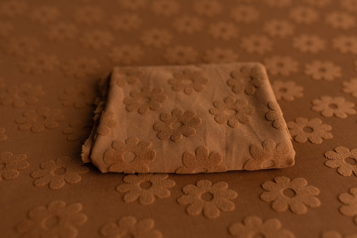 Rust fabric with raised daisy floral texture, styled for newborn photography backdrops and layering props.