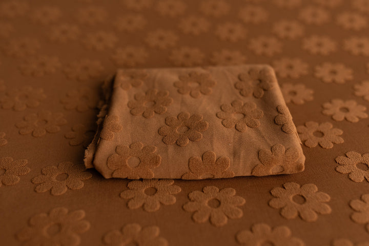 Rust fabric with raised daisy floral texture, styled for newborn photography backdrops and layering props.