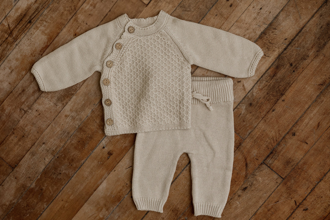 Woodland newborn knit set with cable-knit button cardigan and matching shorts in taupe beige, displayed flat on wooden floor for photography props.